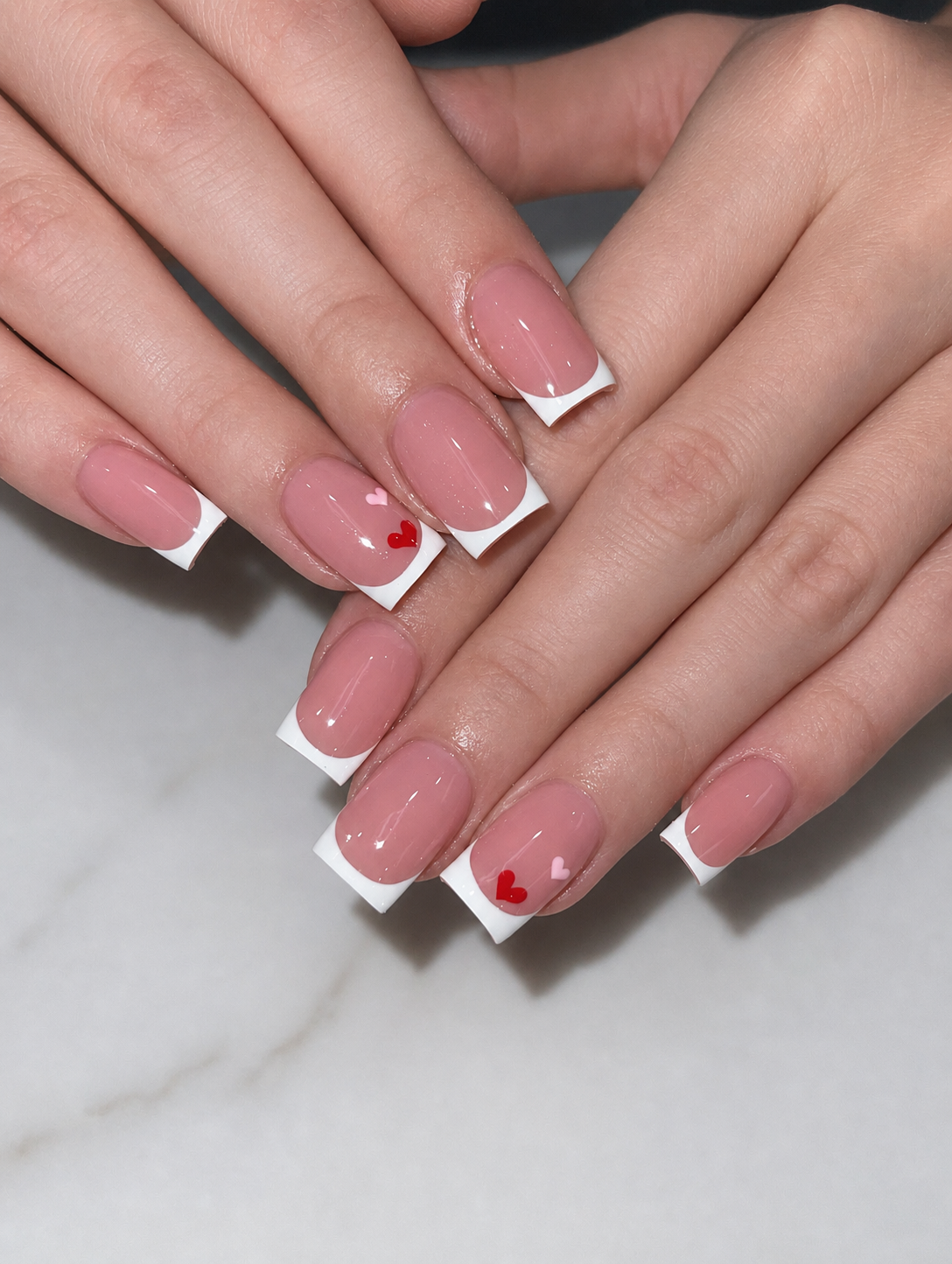 Clean white French manicure with delicate heart details
