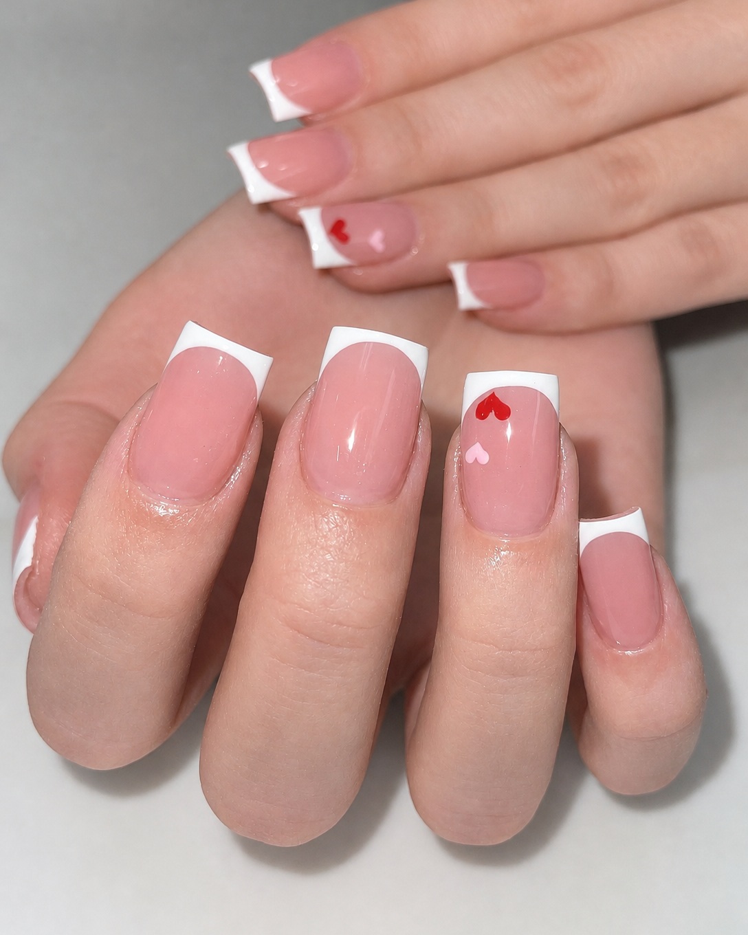 Classic white French manicure with tiny heart details